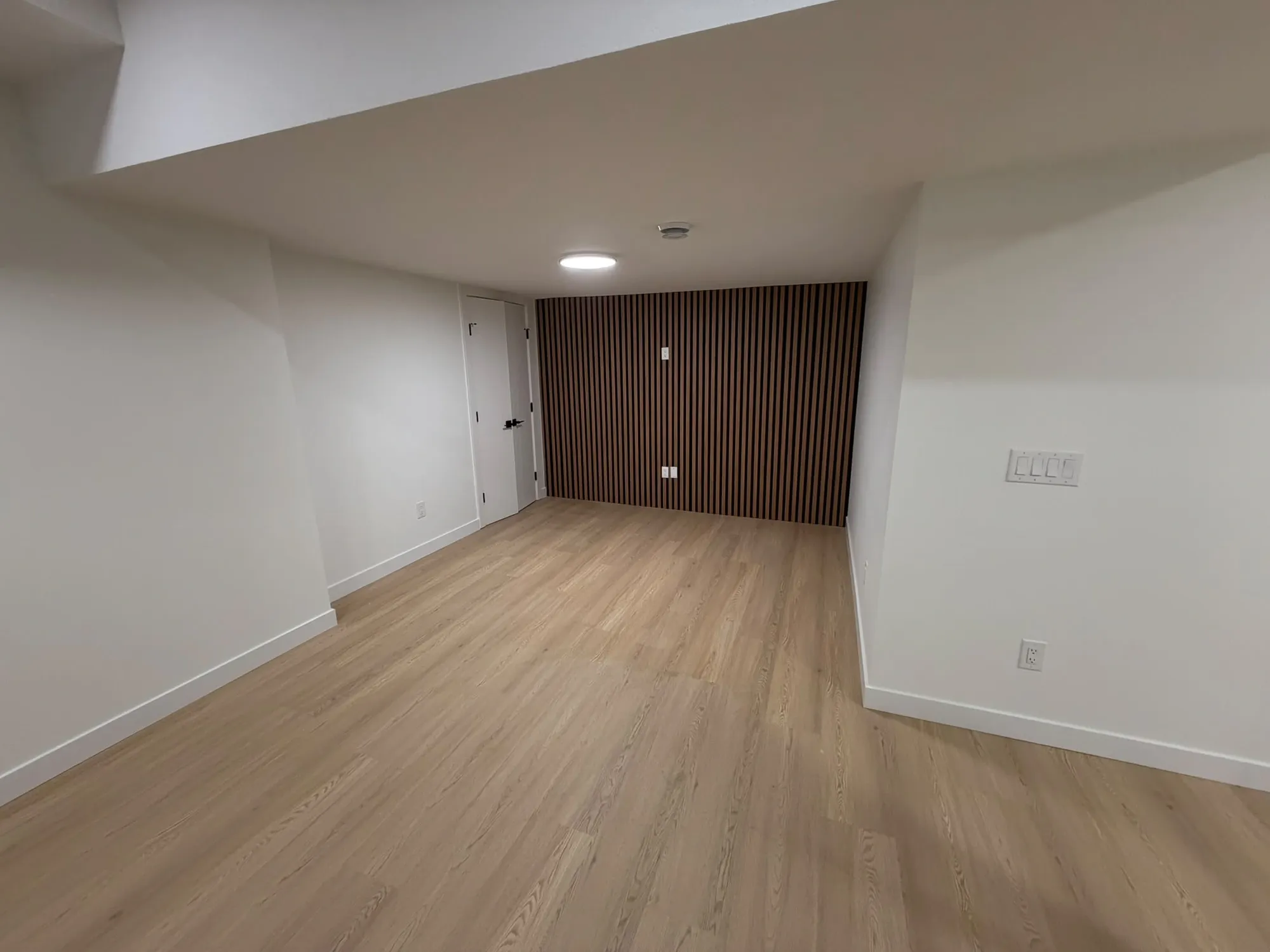Open basement with a walnut slat wall